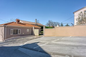 A parking lot with a building that has a tiled roof and a beige wall.
