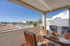 A balcony with a table set for breakfast, a chair, and a view of the surrounding buildings.