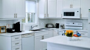 A modern kitchen with white cabinetry, a microwave, a toaster, and a dishwasher.