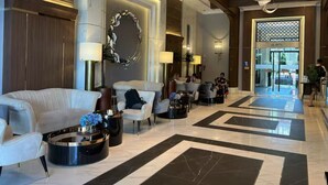 Eine geräumige Lobby mit einem weißen Sofa, Sesseln und einem Couchtisch mit Blumenvase.
