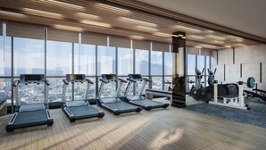 Ein modernes Fitnessstudio mit Laufbändern, Kraftgeräten und Blick auf die Stadt.