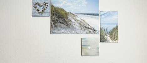 A wall with four framed beach scenes and two Philips speakers.