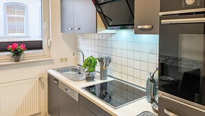 Una cocina moderna con lavavajillas integrado, un lavamanos de acero inoxidable y un horno negro.
