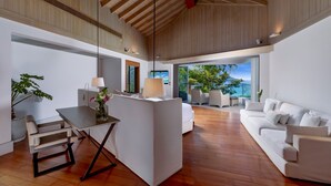 A modern living room with a wooden ceiling, a white sofa, a dining area with a table and chairs, and a view of the outdoors. - Villa Amankara (Karon)
