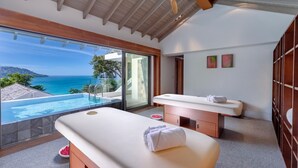 A modern spa room with a large glass window overlooking a pool and the sea. - Villa Amankara (Karon)