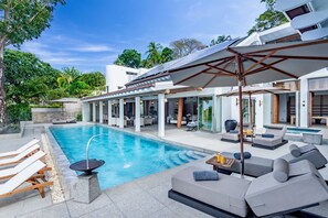 A modern poolside area with a pool, lounge chairs, and a covered seating area. - Villa Amankara (Karon)