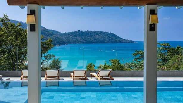 A poolside area with lounge chairs and a view of the sea. - Villa Amankara (Karon)