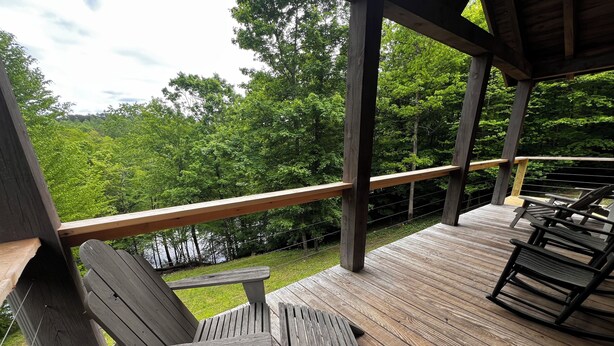 Une terrasse en bois dotée d’une rambarde, qui offre une vue sur une zone boisée.