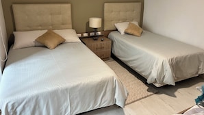 Et hotelværelse med to enkeltsenge, et natbord med lampe og et mønstret tæppe.