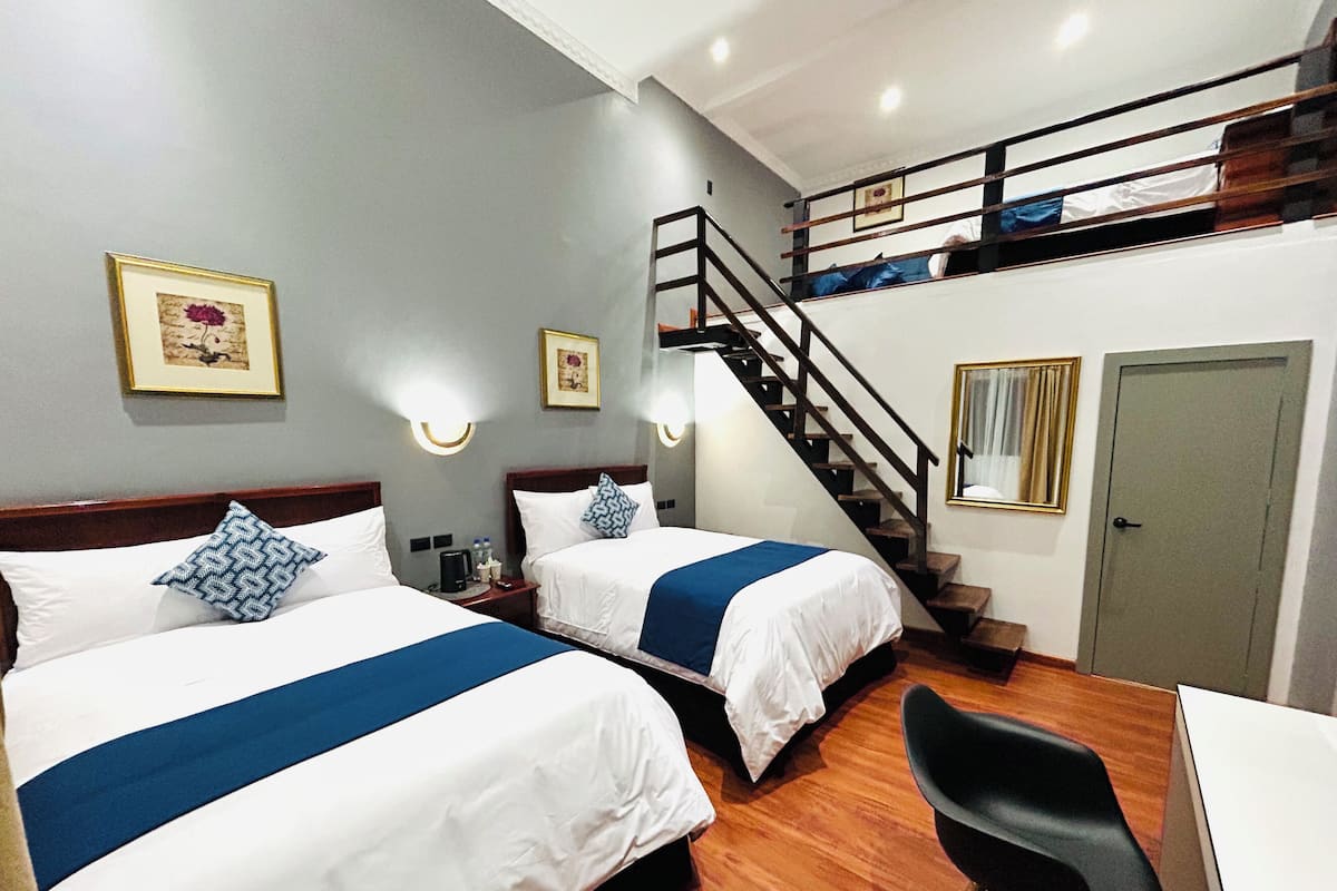 Een hotelkamer met twee bedden, een bureau, een stoel, een trap en een deur.