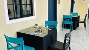 A dining area with a table set for four, surrounded by teal chairs, a black tablecloth, and a small plant on the table. - ACCEL Hotel Casa Nueva (Ibarra)