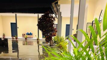 A wet outdoor area with potted plants, a sofa, and a staircase.