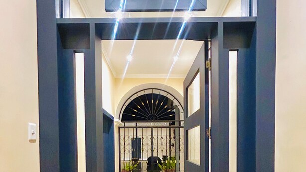 A hallway leading to a gated entrance with a tiled floor and a decorative archway. - ACCEL Hotel Casa Nueva (Ibarra)