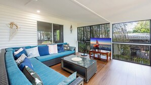 Ein modernes Wohnzimmer mit einem blauen Sofa, einem Couchtisch und einem Fernseher.