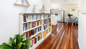 Eine moderne Küche mit integriertem Bücherregal voller Bücher, Holzboden und einem Essbereich mit einer Pflanze.