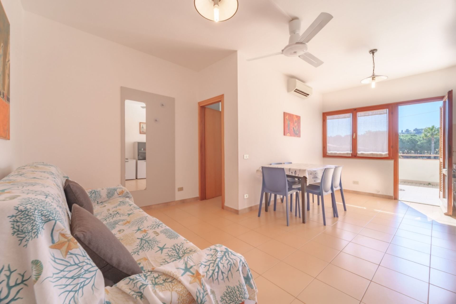 A spacious living area with a sofa, a dining table with chairs, and a ceiling fan.