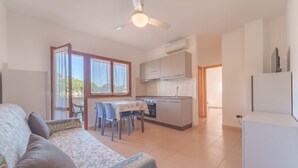 Un espacio habitable compacto con kitchenette, comedor y sofá con estampado.