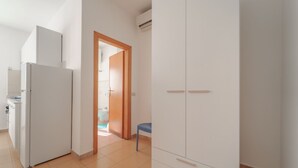 A room with a white wardrobe, a white cabinet, and a blue chair. - APPARTAMENTI GLI ORIZZONTI - ORIZZONTI N MONO 21 (Marina di Campo)