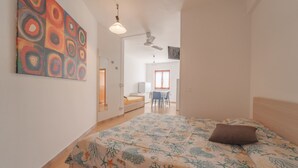 A bedroom with a bed, a ceiling fan, a desk, and a chair in the background. - APPARTAMENTI GLI ORIZZONTI - ORIZZONTI N MONO 21 (Marina di Campo)