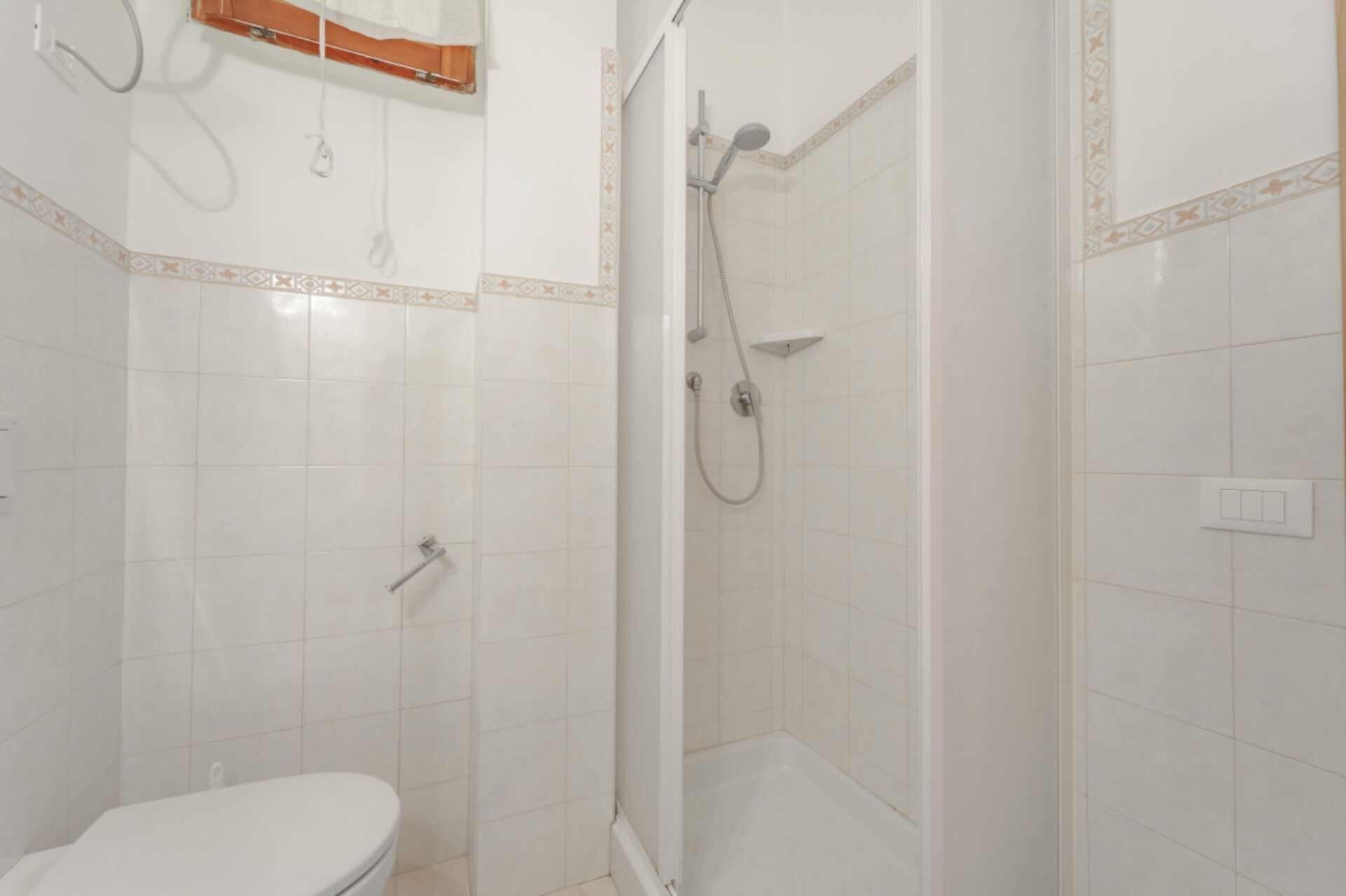 A bathroom with a toilet, a shower with a handheld showerhead, and a corner sink.