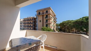 A balcony with a table and chairs, overlooking a multi-story building and trees. - APPARTAMENTI GLI ORIZZONTI - ORIZZONTI N MONO 19 (Marina di Campo)