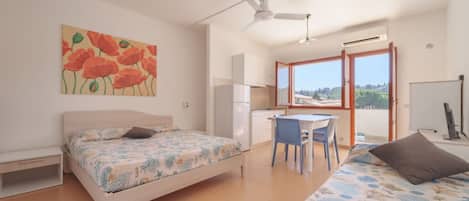 A bedroom with two beds, a desk, and a chair.