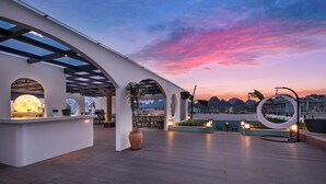 A rooftop terrace with a bar area, seating, and a view of the mountains at sunset. - SYYF Xiang Shan You Yue Jiudian Guilin (Guilin)
