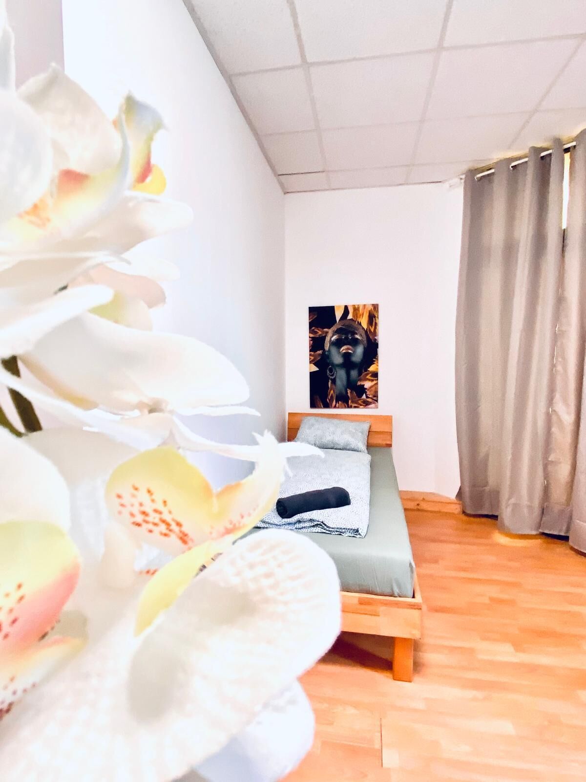 Un dormitorio con una cama, un cuadro en la pared y una ventana con cortinas.