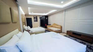 Een hotelkamer met een groot bed, een slaapbank, een televisie en een bureau.