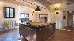 Una cocina con una isla central, una lámpara colgante y techo rústico.