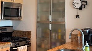 Une cuisine moderne dotée d’appareils électroménagers en acier inoxydable, d’un plan de travail en granit, d’un réfrig érateur à deux portes et d’une horloge murale.