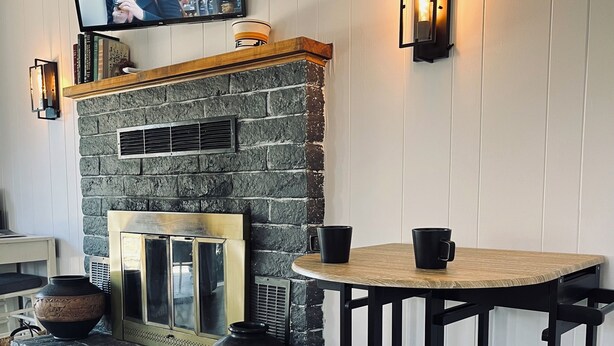 Een knusse bar met een stenen openhaard, twee krukken en een televisie aan de muur.