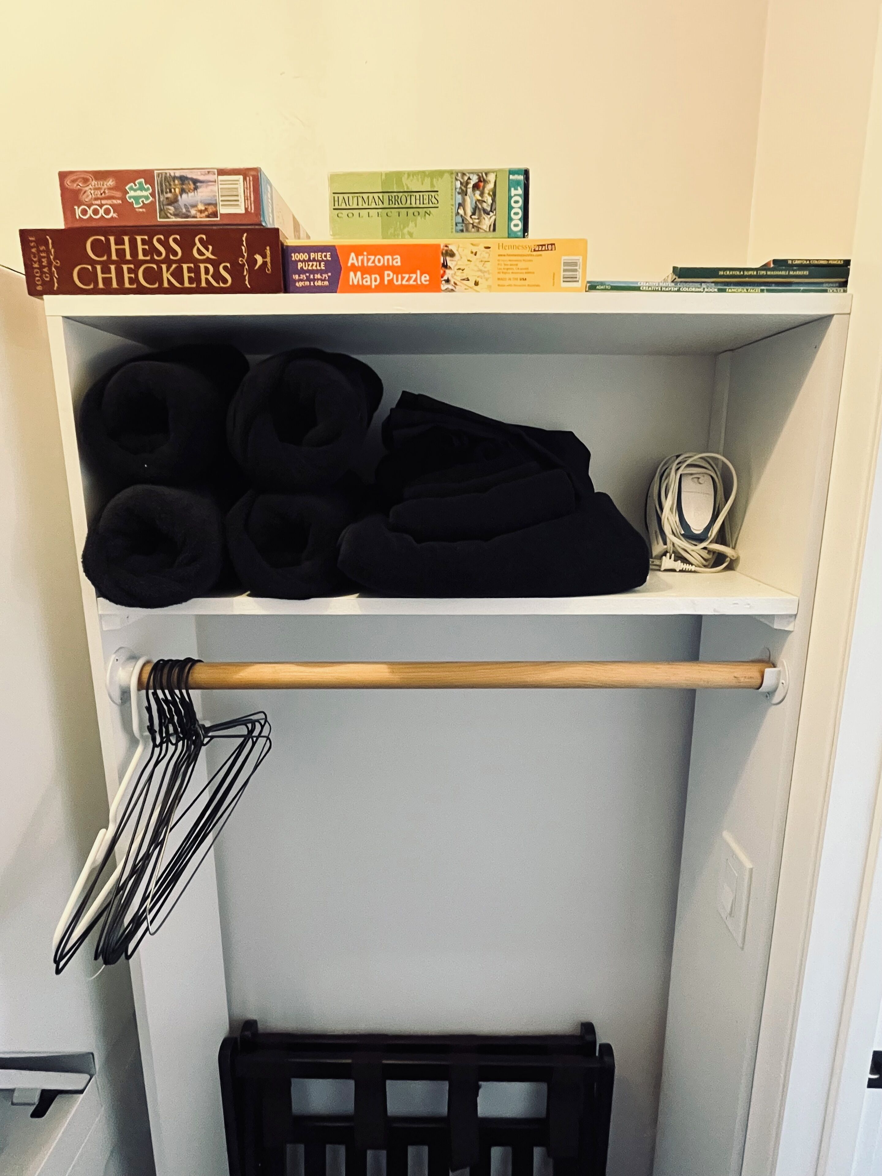 A storage shelf with various items including a chess and checkers box, a 1000-piece puzzle, and a map puzzle.