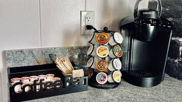 A kitchen counter with a coffee station including a Keurig coffee maker, a mug holder, and a coffee pod organizer.