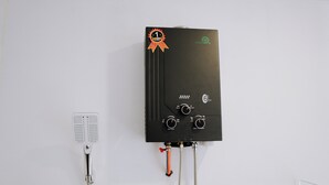 Un chauffe-eau noir fixé sur un mur blanc, muni de boutons de commande et d’une vanne rouge.