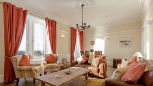 A living room with a wooden coffee table, leather sofas, and plaid chairs. - Portpatrick House by Interhome (Portpatrick)