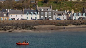 A coastal town with stone buildings, a sandy beach, and a boat on the water. - Portpatrick House by Interhome (Portpatrick)