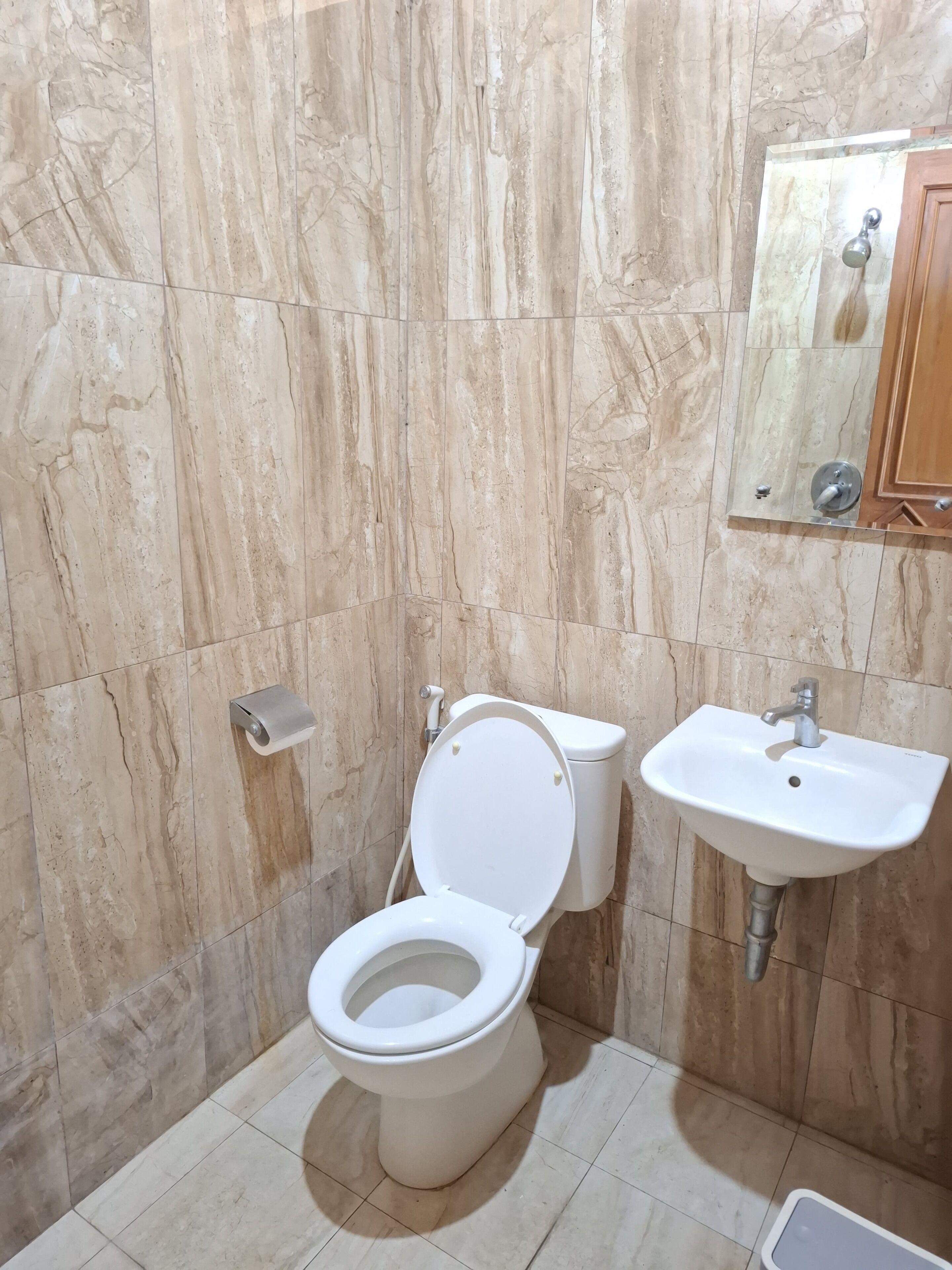 Un baño con inodoro, lavabo y paredes de mármol.