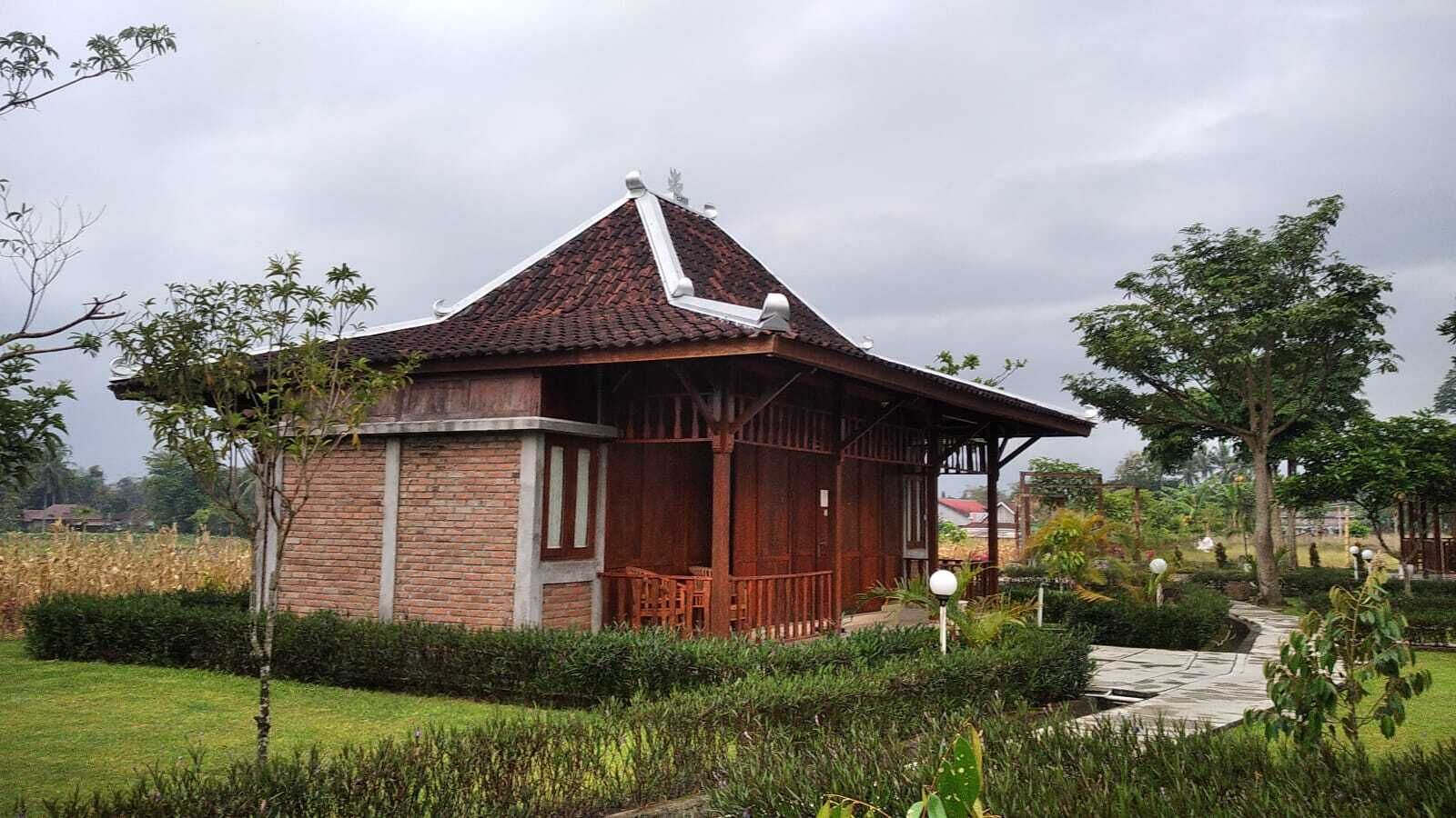 A traditional wooden structure with a tiled roof, surrounded by a well-maintained garden and a paved pathway.