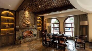A stone fireplace with a mantel, a dining area with a table and chairs, and a large arched window.