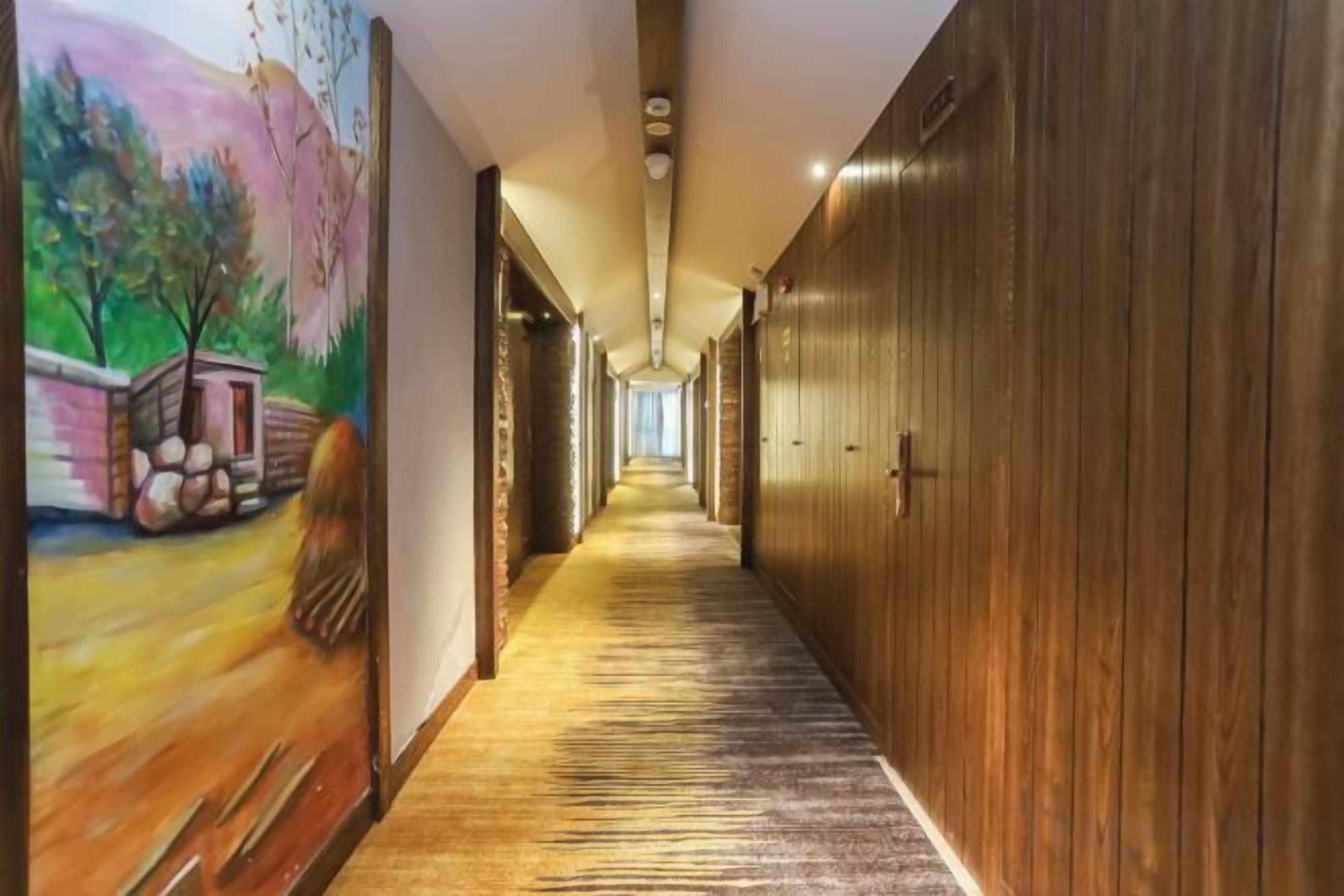 A long hallway with wooden paneling and a carpeted floor, leading to a door at the end.