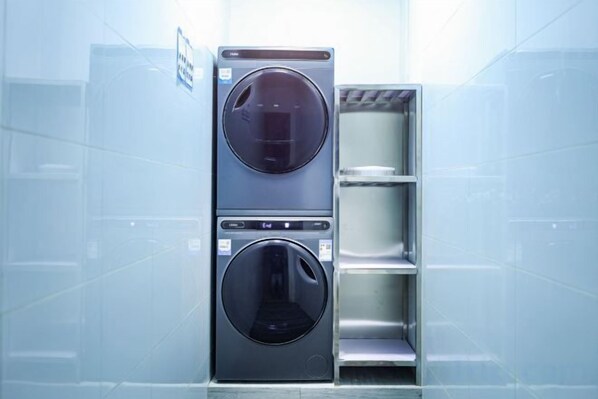 A stacked washer and dryer unit in a modern, tiled room.