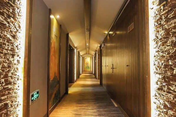 A hotel corridor with wooden walls, a carpeted floor, and doors leading to rooms. - World Smart Hotel (ShanghaiFudan University of Finance and Economics Dabaishu Subway Station) (Shanghai)