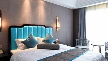 Een hotelkamer met een groot bed, een nachtkastje, een stoel en een klein tafeltje.