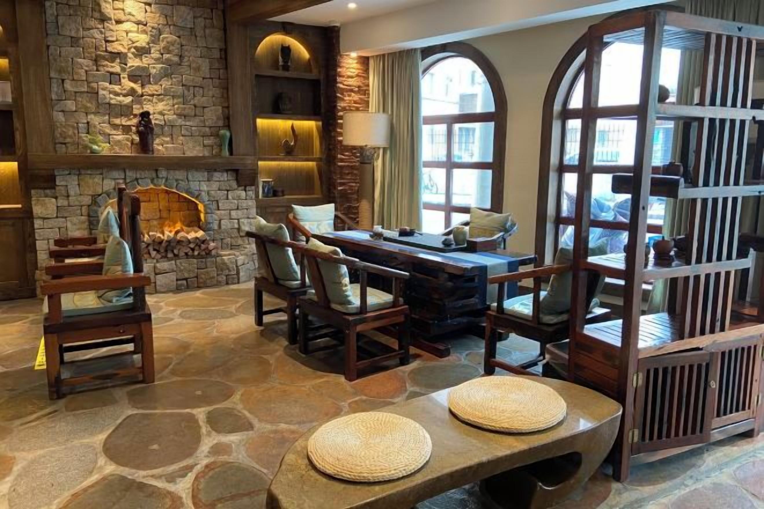 A stone-floored room with a fireplace, wooden furniture, and a view through a window.