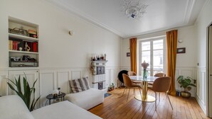 Ein Zimmer mit Esstisch, Stühlen, einer Couch, einem Bücherregal und einem Kamin.