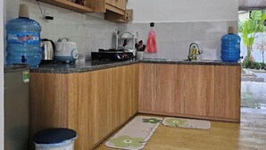 A kitchen with wooden cabinets, a countertop, a sink, and a window. - Mit homestay (Hue)