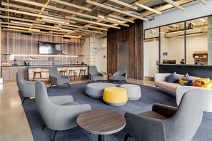 Relax in the lounge area with sofas, armchairs, and ottomans, featuring a large TV and kitchen bar.