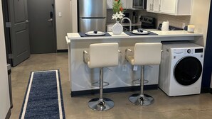 A modern kitchen with white cabinets, stainless steel appliances, and a central island with bar stools. - Cozy and Clean 1 Bedroom Apt centrally located in Downtown Birmingham, Near UAB (Birmingham)