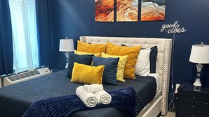 A bedroom with a large bed, two bedside tables, a window with curtains, and a wall with abstract art. - Cozy and Clean 1 Bedroom Apt centrally located in Downtown Birmingham, Near UAB (Birmingham)